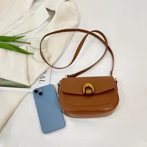 Minimalist brown saddle bag with gold horseshoe clasp and leather strap for women