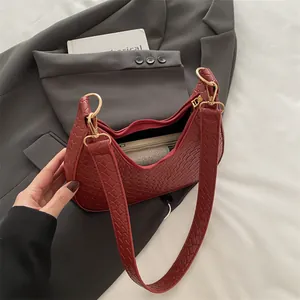Deep red woven crescent hobo bag shown on a gray blazer with a minimalist aesthetic