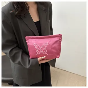Detail of pink satin clutch bag featuring intricate butterfly embroidery and silk sheen