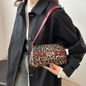 Sac baguette imprimé léopard avec bandoulière rouge et détail mors porté par mannequin