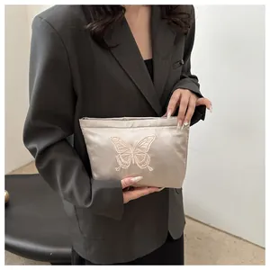 Close-up of elegant butterfly embroidery on luxury champagne gold satin pouch bag