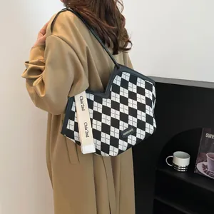 Dettaglio della borsa tote a scacchi con tracolla logata ed etichetta di moda