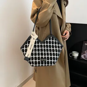 Dettaglio della borsa tote in tweed a scacchi con apertura a V e tracolla intrecciata
