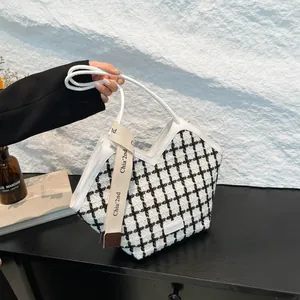 Dettaglio della borsa tote a quadri bianchi e neri con finiture in pelle e cinturino