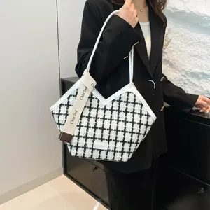 Dettaglio della borsa tote in tweed bianco e nero con manici in pelle bianca e taglio a V