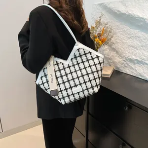 Dettaglio della borsa tote in tweed a quadri bianchi e neri con logo Chia' 2nd sulla tracolla