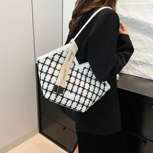 Dettaglio della borsa tote in tweed con piping e tracolla in tela firmata