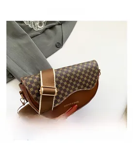 Close-up of saddle bag featuring monogram pattern and wide fabric shoulder strap