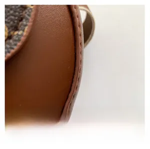 Close-up of textured leather brown saddle bag with monogram pattern and stitching