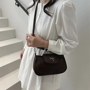Borsa a tracolla in pelle opaca marrone scuro con fiocco in metallo argento indossata da modella