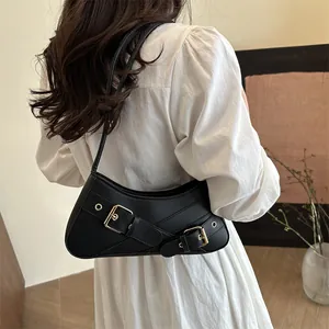 Black Y2K underarm bag with decorative straps and gold buckles on a female model