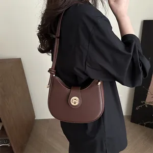 Elegant dark brown leather hobo shoulder bag with a gold round clasp shown on model
