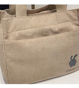 Détail du sac cabas en velours côtelé kaki avec broderie lapin et poche latérale