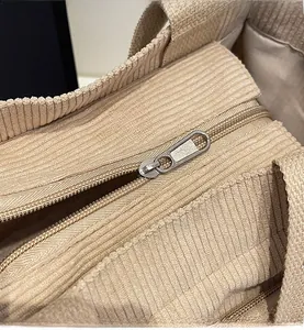 Détail d'une fermeture éclair en métal sur un sac fourre-tout en velours côtelé beige
