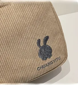 Détail du lapin brodé et du lettrage sur le tissu en velours côtelé marron du sac
