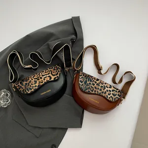 Detail of black and brown saddle bags with leopard print flap and wide woven straps