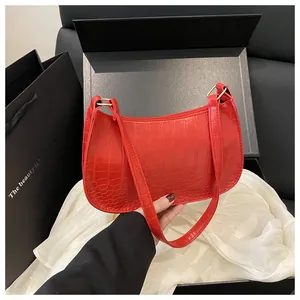 Detailed view of red crocodile pattern handbag with elegant gold metal buckles and strap