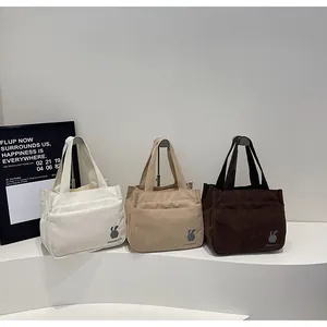 Détail des sacs cabas en velours côtelé avec broderie lapin en blanc, beige et marron