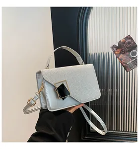 Close-up of glittery silver crossbody bag featuring a modern geometric metal buckle
