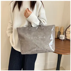 Dettaglio della borsa tote grigia impermeabile in PVC con scritta bianca e manico