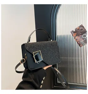 Detail of black woven crossbody bag featuring glitter sequins and gold geometric buckle