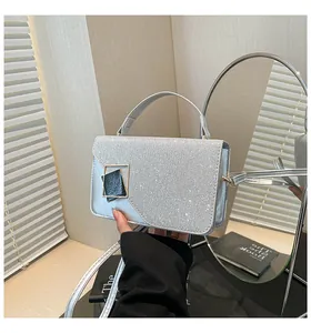 Detail of silver glitter handbag featuring a modern gold-black metal square clasp and handle