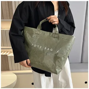 Détail d'un grand sac cabas en PVC vert brillant avec texte blanc TOTE BAG en intérieur