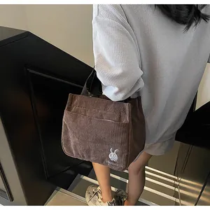 Gros plan du sac fourre-tout en velours côtelé marron avec broderie lapin et texte