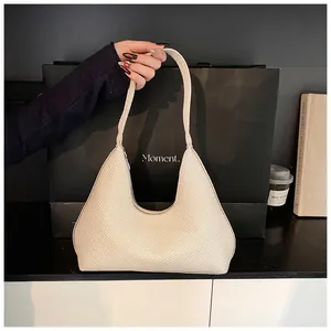Close-up of beige woven hobo shoulder bag with textured finish in minimalist studio setting