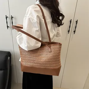 Sac cabas en paille avec surpiqûres en cuir marron porté à l'épaule, vue principale