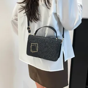Women's black crossbody bag with shimmering sequins and gold geometric buckle hardware