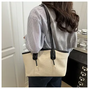 Detailed close-up of cream woven tote bag featuring black leather straps and knot details