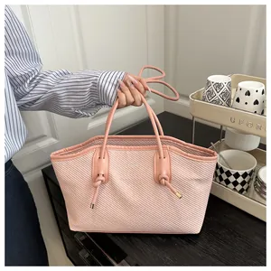 Close-up of pink tote bag showing diagonal texture, knot detail, and slim handle strap