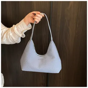 Detail of light blue crescent bag with woven texture and wide shoulder strap