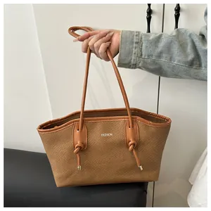 Detail of woven tote bag featuring brown leather trim and white FASHION lettering