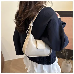 Detail view of beige crescent underarm bag with adjustable strap and silver buckle