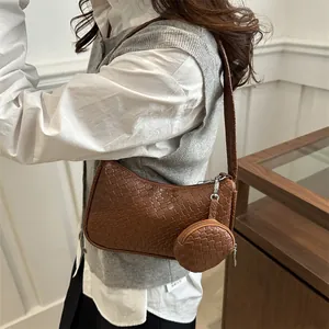 Brown woven hobo bag with matching round coin purse shown in a stylish indoor setting
