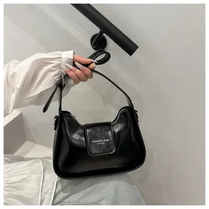 Close-up of black leather underarm bag with silver buckle and embossed fashion lettering