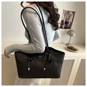 Detail of black tote bag featuring textured fabric and silver Fashion logo with shoulder strap