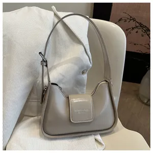 Detailed close-up of beige moon bag with leather texture on white corduroy suit