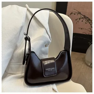 Close-up of a dark brown patent leather shoulder bag with a silver buckle and magnetic flap