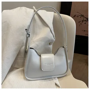 Detail view of cream leather shoulder bag with silver buckle and fashion logo on a chair