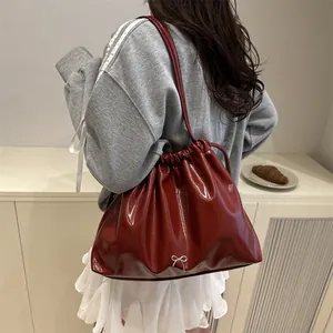 Sac seau plissé rouge foncé avec nœud argenté et bandoulière à la finition brillante