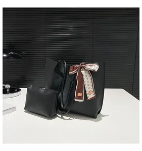 Detailed view of the black matte leather tote set with a decorative silk bow scarf