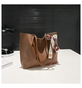 Detail of classic brown leather tote bag with a patterned silk scarf on the handle