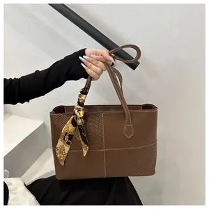 Close-up of brown tote bag with animal texture, white stitching and silk scarf wrap