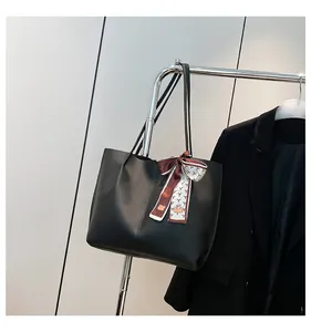 Detail of black leather tote bag with printed silk scarf handle hanging on metal rack
