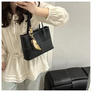 Detail of black tote bag featuring animal pattern textures and silk scarf handle decor
