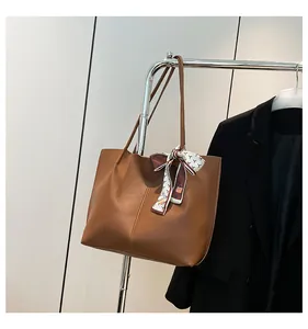 Close-up of brown leather tote bag with silk scarf detail hanging on a metal rack
