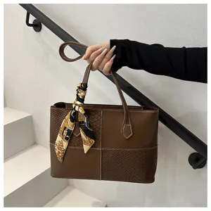 Detail of dark brown patchwork tote bag with snake texture and decorative silk scarf